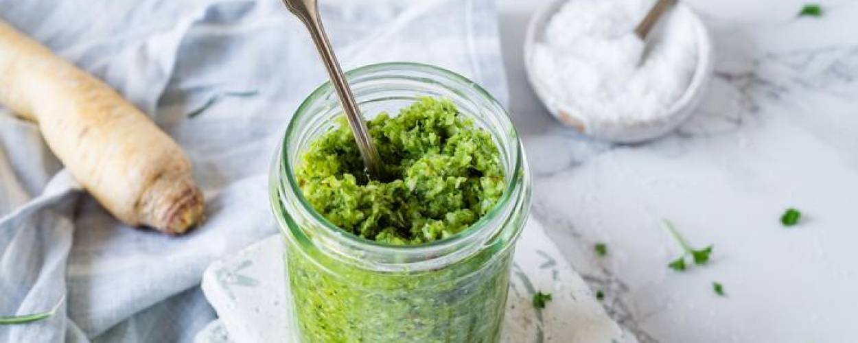 Grünes Pesto im Glas mit Löffel und Salz