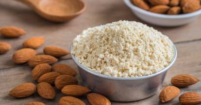 Mandelmehl in einer Schale daneben ganze Mandeln auf einem Holztisch