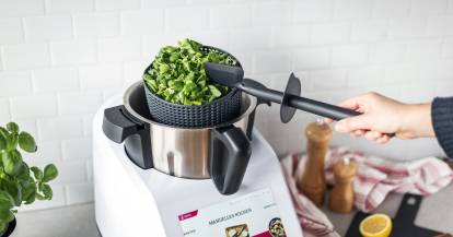 Salatschleuder wird mit dem Spatel aus dem Mixbehälter genommen.