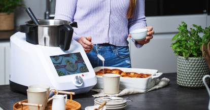 Junge Frau in Küche mit Monsieur Cuisine backt Zimtschnecken