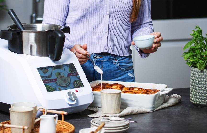 Junge Frau in Küche mit Monsieur Cuisine backt Zimtschnecken